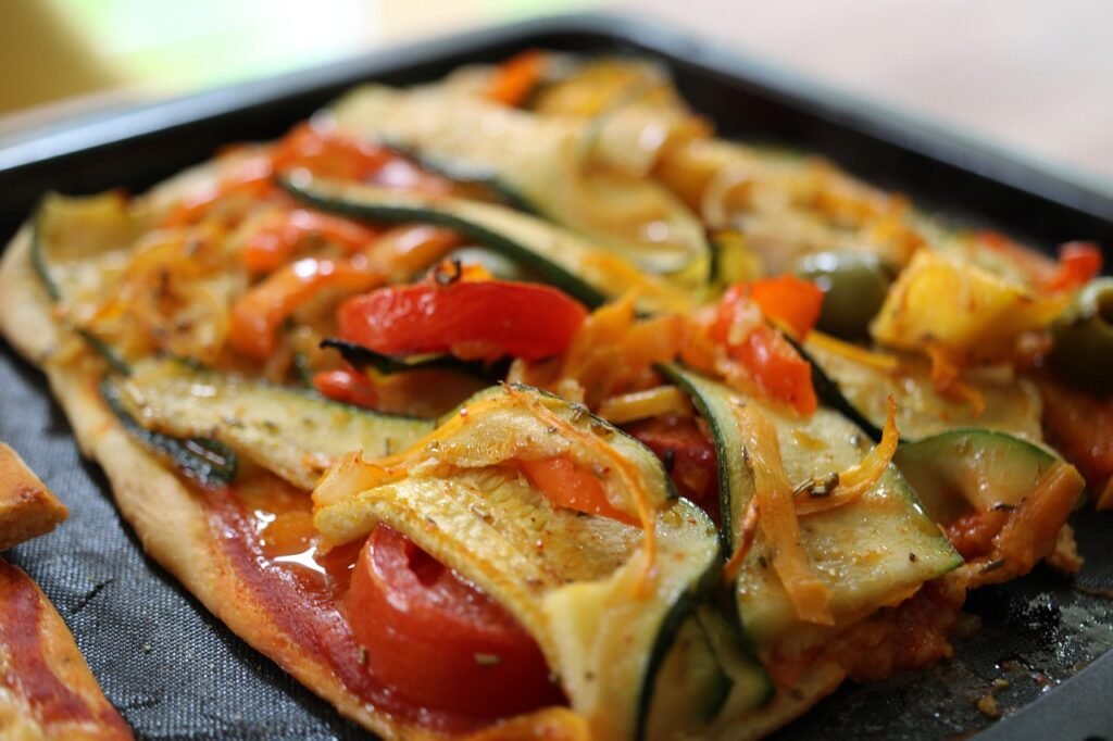 deliciosa pizza vegetariana es una opción perfecta para una comida ligera y saludable. Con una base crujiente y una combinación de verduras frescas y sabrosas, ¡esta pizza casera te conquistará! 'Pizza casera con base delgada, cubierta con salsa de tomate, rodajas de calabacín, pimiento rojo y aceitunas negras